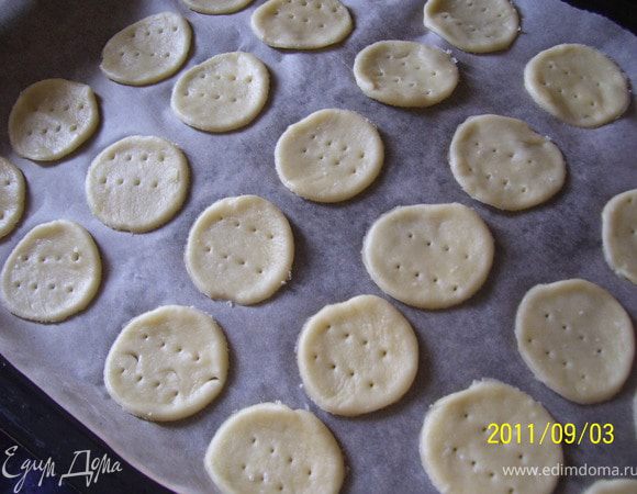 Раскатать тесто в очень тонкий пласт - до прозрачности на бумаге для выпечки. Затем вырезать печенье-пуговки. Проколоть вилкой. Уложить на противень, присыпать солью. 