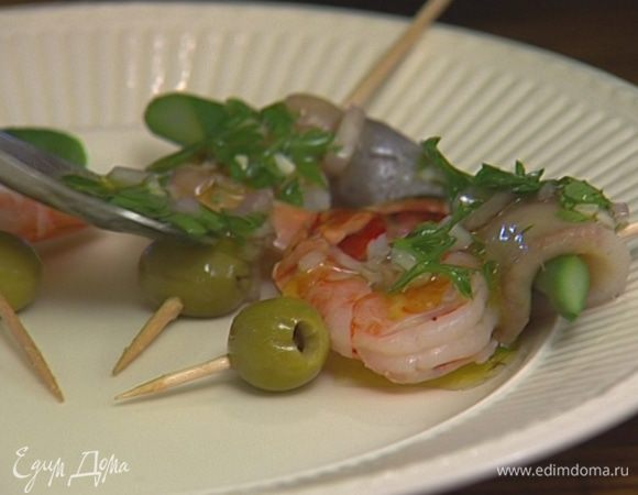 Завернуть каждый кусочек спаржи в сельдь, проткнуть коктейльной палочкой, надеть на палочку креветку и оливку. Полить получившиеся «шашлычки» заправкой и поперчить. 
