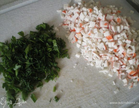 Мелко нарезать крабовые палочки и зелень.