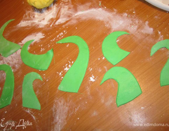Раскатать зеленую мастику и вырезать, произвольно, завитушки.