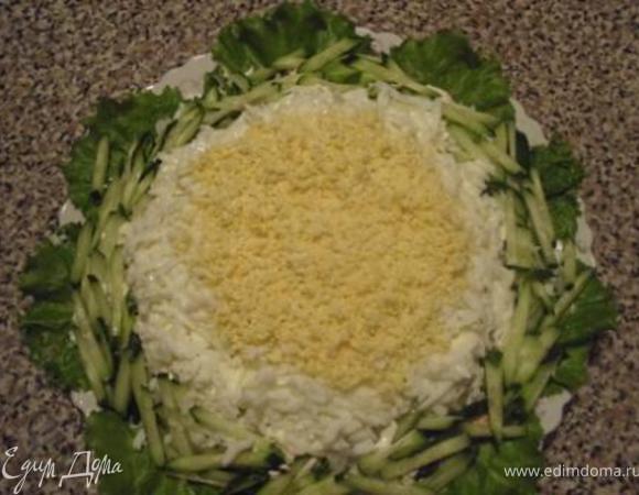 На крупной терке натереть белок, в центр - на мелкой терке желток. По краю выложить огурчики.
