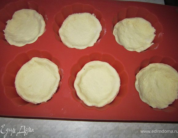 Тесто раскатать, вырезать формочкой круглые заготовка, по две заготовки на один пирожок. Выложить первый кружок в формочки для запекания.