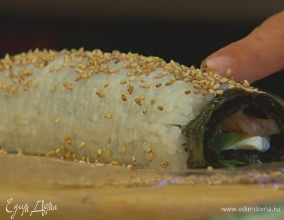 Свернуть ролл, ровно удерживая начинку, затем раскрутить коврик, удалить пленку и разрезать ролл на шесть частей. 

