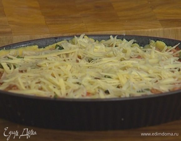 Выложить начинку в форму с тестом, присыпать натертым сыром и запекать в разогретой духовке 30–35 минут.