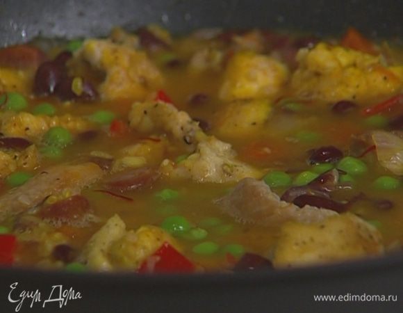 Залить подогретым куриным бульоном так, чтобы все ингредиенты были покрыты жидкостью, перемешать, накрыть крышкой и тушить 15–18 минут до готовности риса.