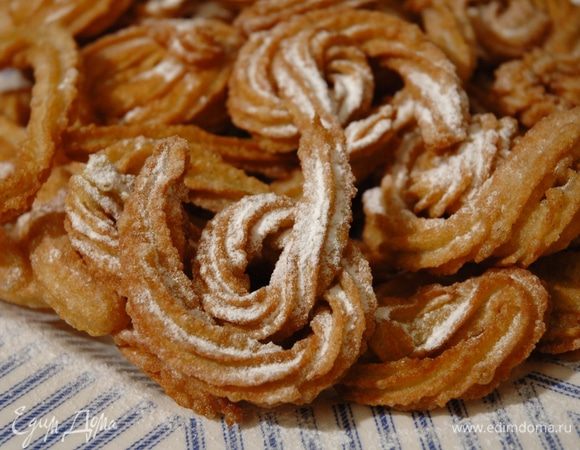 Горячие чуррос выкладывать шумовкой на бумажное полотенце, чтобы удалить излишек жира, затем присыпать сахарной пудрой.