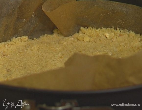 Застелить форму смазанной сливочным маслом бумагой для выпечки, выложить 2/3 теста, слегка уплотнить его и отправить на 10 минут в разогретую духовку.