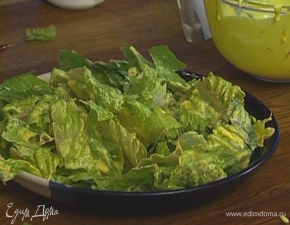 Листья салата крупно нарезать, выложить на блюдо, полить половиной йогуртовой заправки.