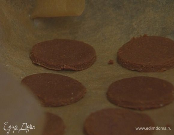  Удалить верхний слой бумаги и с помощью рюмки вырезать из теста небольшие кружки. 