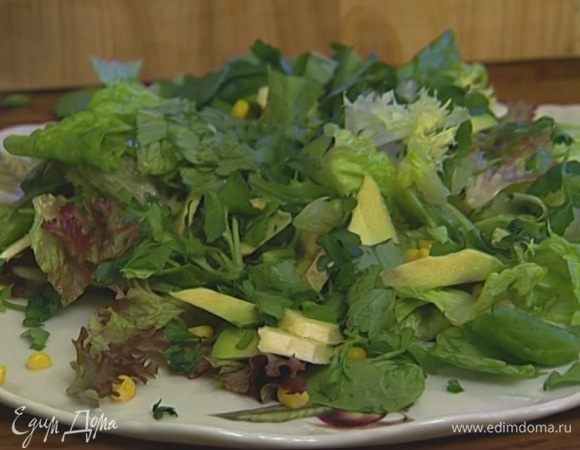 Присыпать листья салата сладкой кукурузой, петрушкой и базиликом, выложить сверху кусочки авокадо.