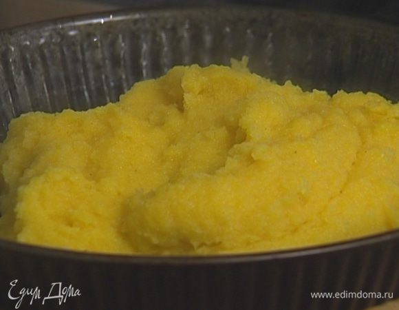 Смазать круглый неглубокий противень растительным маслом, выложить в него поленту, равномерно распределить и оставить до застывания. 