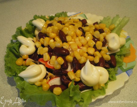 Ветчину, крабовые палочки и огурчики нарезать тонкой соломкой. Выложить все ингредиенты слоями в произвольной форме на листья салата. Украсить майонезом. 