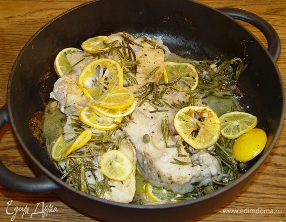 Отправить рыбу в разогретую духовку, через 5 минут уложить на нее кружки лимона и запекать еще около 20 минут.