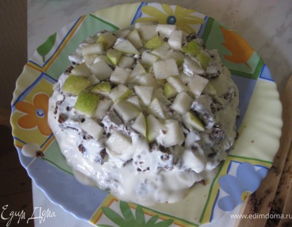 Выложите первый слой из кубиков бисквита, обмазанных в креме (от центра к краям). Затем слой из ананаса и орехов.