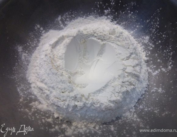 В большую кастрюлю горкой насыпать 2 стакана муки и сделать углубление.