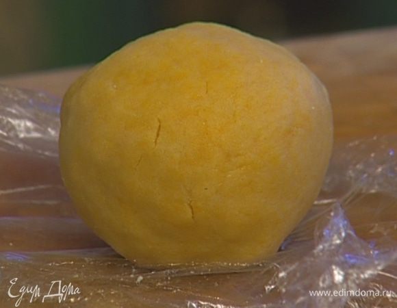 Добавить 2 ст. ложки сахарной пудры, 2 желтка и 1 ст. ложку ледяной воды, вымесить слегка тесто. Скатать из него шар, завернуть в пищевую пленку и положить на час в холодильник.