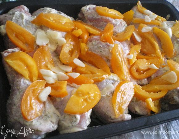 На помидорах сделать крестообразные надрезы, опустить в кипяток, обдать холодной водой, снять кожицу. Помидоры нарезать дольками.Смешать помидоры, чеснок, 1 ч. л. прованских трав,  добавить соль и перец по вкусу.Выложить половину овощной смеси в глубокую форму для запекания, приправить оливковым маслом. Курицу разрезать на порционные куски,удалить лишний жир. Измельчить оставшийся чеснок с оставшимися прованскими травами, солью, перцем и 2 ст. л. масла, натереть куски курицы со всех сторон. Поместить их в форму на овощной слой, поверх выложить
оставшиеся овощи. Поставить в разогретую до 190 °С духовку, запекать до готовности, около 1 ч 10 мин.
