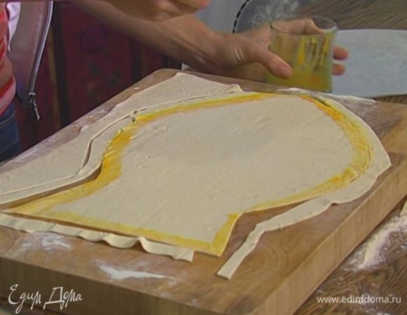 Желток слегка взбить, смазать им тесто и уложить на края «рыбы» полоски теста, чтобы получился бортик. 