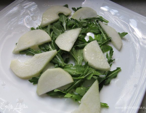 Руколу выложить на тарелку. С верху разложить кусочки груши, порезанные на тоненькие пластинки.