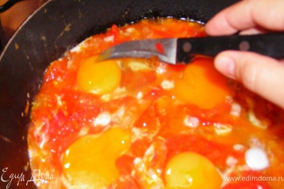 Как только помидоры становятся мягкими солим, разбиваем по одному яйца сверху. Важно не мешать и не взбивать. Желток протыкаем ножиком.