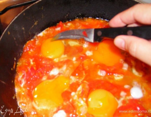 Как только помидоры становятся мягкими солим, разбиваем по одному яйца сверху. Важно не мешать и не взбивать. Желток протыкаем ножиком.