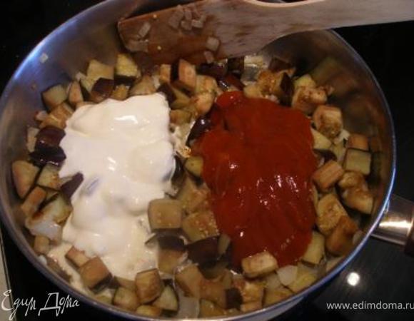 Добавить сметану, томатную пасту и специи. Можно еще добавить зелень и кунжутные семена. Готовить еще несколько минут, - до готовности баклажан. 