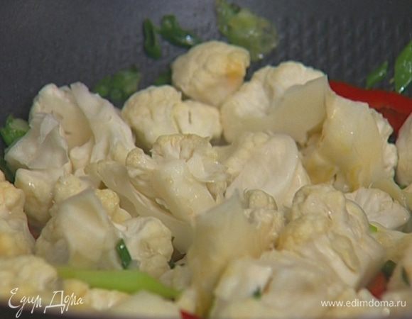 Разогреть в сковороде вок арахисовое масло, добавить чеснок, чили, зеленый лук, имбирь и цветную капусту, перемешать.