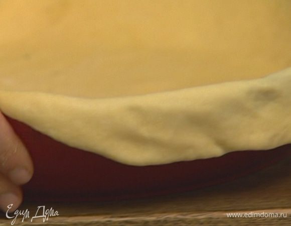 Неглубокую, тяжелую форму для выпечки смазать растительным маслом и выложить в нее раскатанный пласт теста так, чтобы края теста слегка выступали за края формы. 