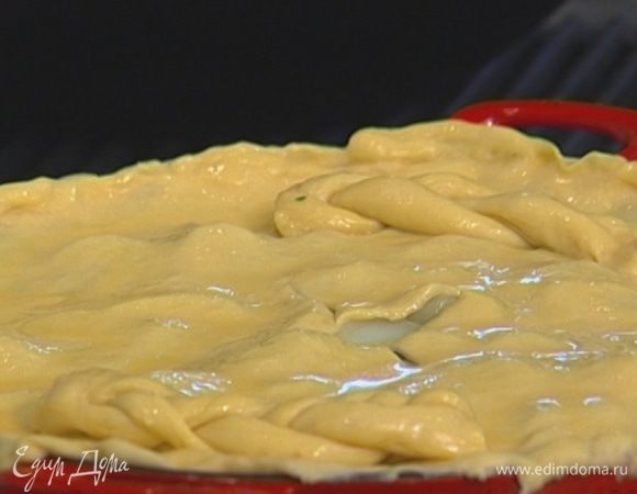 Сделать крестообразный надрез по центру пирога, смазать тесто желтком с молоком.