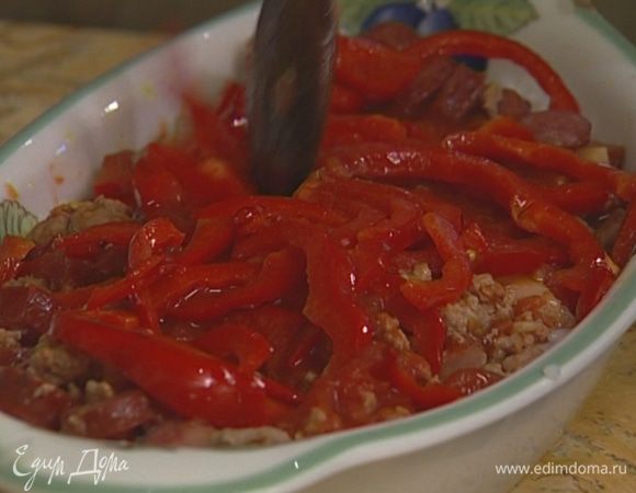 Форму, в которой будут подаваться яйца фламенко, смазать оливковым маслом. Выложить в форму слоями рис, мясной фарш с колбасками, оставшиеся томаты и сладкий перец.