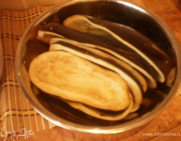 Баклажаны разрезаем вдоль напополам. Вынимаем сердцевину, замачиваем в соленой воде на 30 минут.