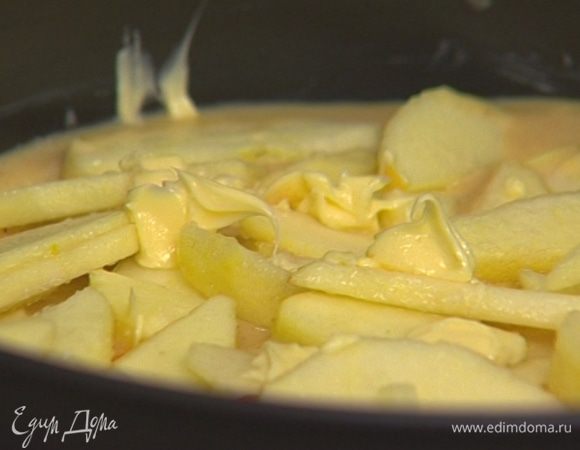 Смазать разъемную форму для выпечки сливочным маслом и наполнить ее тестом. На тесто выложить дольки яблок, сверху — кусочки сливочного масла. 