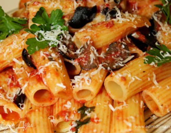 Отвариваем ригатони как указано на упаковке, в данном случае 12-15 минут в соленой воде. Отдельно на сковороде обжариваем на оливковом масле мелко нарезанный чеснок, лук. Помидоры натираем на терке или пюрируем в блендере. маслины режем на половинки, четвертинки, можно оставить целыми. Добавляем томатное пюре на сковороду и тушим на медленном огне минут 15- 20, добавляем нарезанные оливки, итальянские травы, соль, перец, и томим соус еще в течении 15 минут. Добавляем соус к ригатони, перемешиваем, посыпаем зеленью и тертым пармезаном.