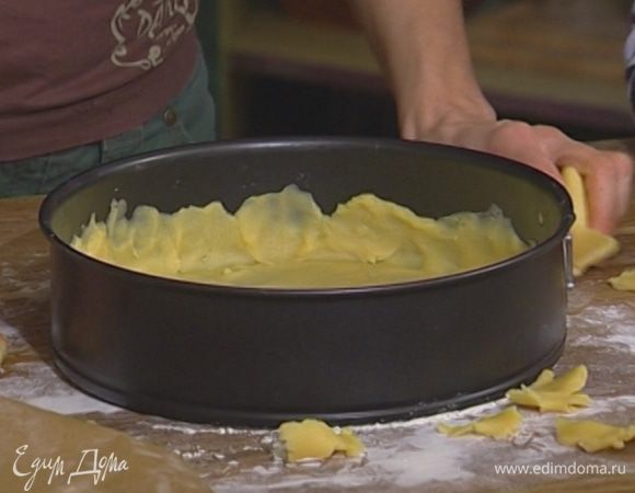 Поместить тесто между двумя листами бумаги для выпечки и раскатать в тонкий пласт, затем выложить в смазанную оставшимся сливочным маслом разъемную форму, так чтобы получился корж с бортиком.