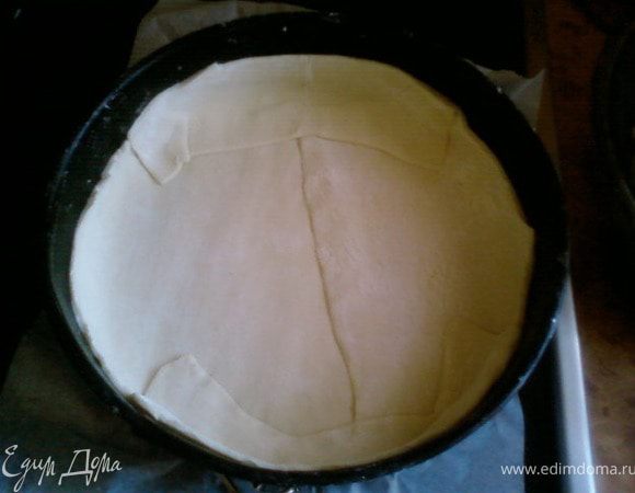 Размороженное слоеное тесто раскатать, форму застелить бумагой для выпечке,взбрызнуть холодной водой и уложить в неё тесто сделав при этом края до середины бортиков формы.