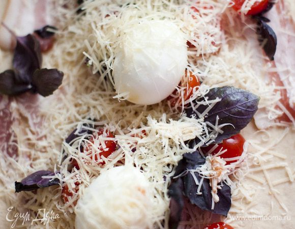 Дрожжевое кольцо. Раскатать одну часть теста в продолговатый большой блин. Разложить по всей его поверхности бекон. В ряд выложить вареные яйца. Добавить базилик и нарезанные большими кусками помидоры (без семян). Сверху засыпать тертым сыром. Завернуть все в виде колбаски и сделать кольцо.