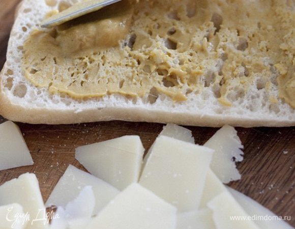 Хлеб надрезать сбоку, не прорезая до конца, затем раскрыть, сбрызнуть оливковым маслом и смазать горчицей, уложить на одну половину хлеба листья салата, мясо и сыр, накрыть второй половиной и разрезать чиабатту на 4 части.