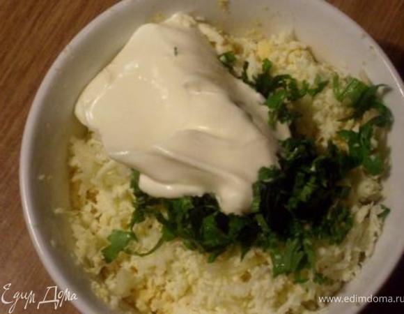 Желтки размять вилкой в мисочке, туда же потереть на мелкой терке сыр и чеснок, добавить мелко порубленную зелень, немного майонеза, тщательно перемешать и  скатать шарики слегка увлажненными руками. 