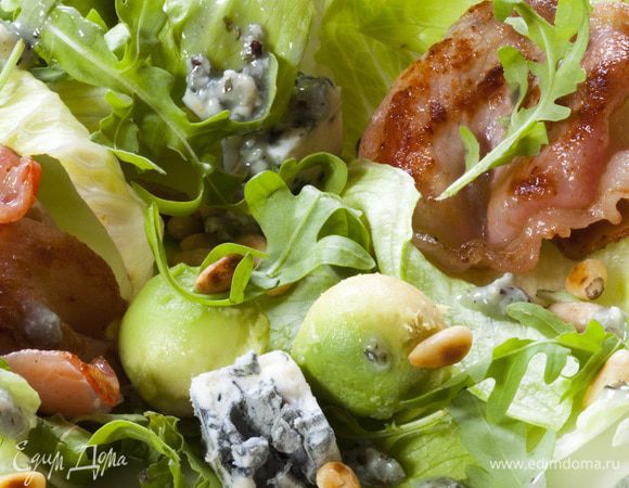 Листья салата выложить на большую тарелку, сверху посыпать кедровыми орехами, разложить бекон и сыр.