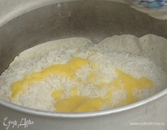 Выложить рис на лаваш, долить немного воды (она должна только покрывать рис), добавить топленое масло и шафран, накрыть крышкой и томить на очень медленном огне около 20 минут. 