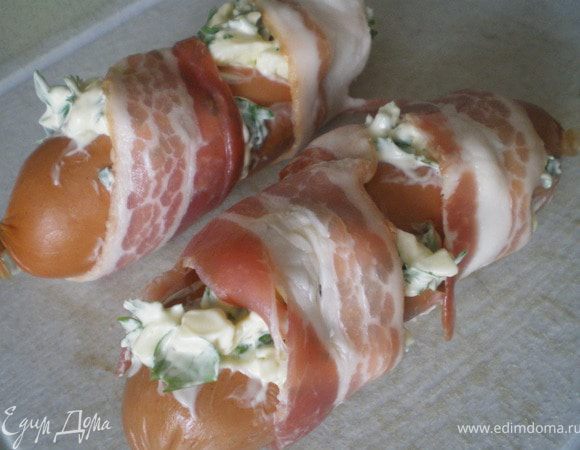 Обвернуть ломтиками бекона сардельки.