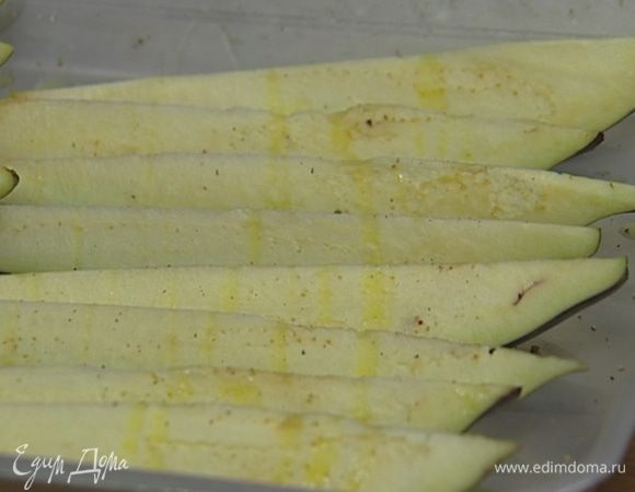 У баклажанов удалить плодоножки и разрезать каждый вдоль на восемь частей, уложить в противень срезами вверх, сбрызнуть растительным маслом, посолить и поперчить.