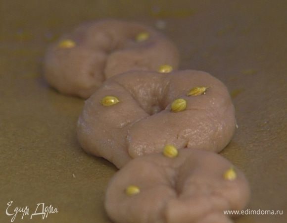 Скатать из теста небольшие тонкие колбаски, соединив концы так, чтобы получились бублики-рогалики. Воткнуть в каждый рогалик по нескольку семян фенхеля или аниса.