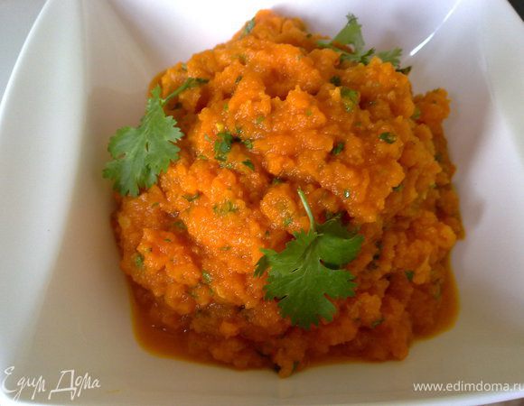 Морковь и чеснок очистить, отварить в воде до готовности. Кумин растереть в ступке. 
Отправить в блендер с парой ложек жидкости в которой она варилась и оливковым маслом. Достаточно грубо взбить. 
Посолить, добавить специи, мелко порезанную зелень, лимонный сок (уксус) и хорошо перемешать. Подавать.
