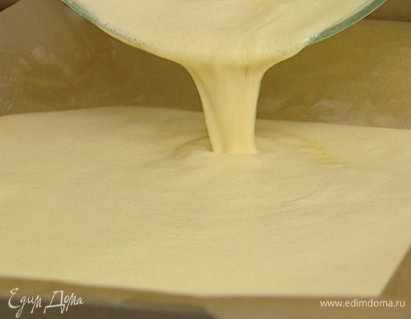 Глубокий большой противень выстелить бумагой для выпечки так, чтобы получились бортики, смазать бумагу сливочным маслом и вылить в противень тесто. 