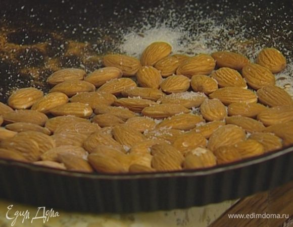 Миндаль поместить в форму для выпечки, посыпать кунжутным семенем, тмином, корицей, сахаром, измельченным пеперончино, солью, полить 1‒2 ч. ложками орехового масла и все перемешать.