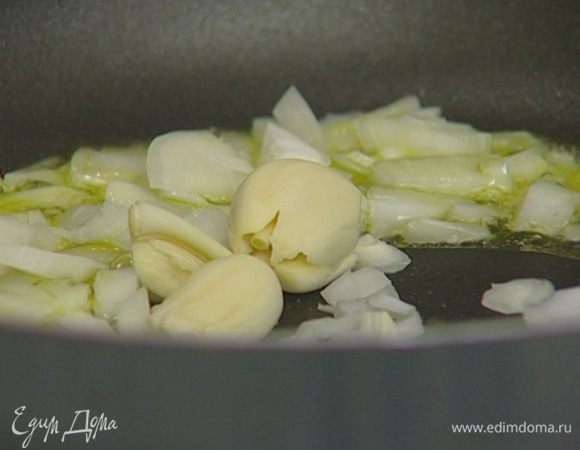 Приготовить соус: в тяжелой сковороде разогреть 3–4 ст. ложки оливкового масла и обжарить лук и чеснок до прозрачности.