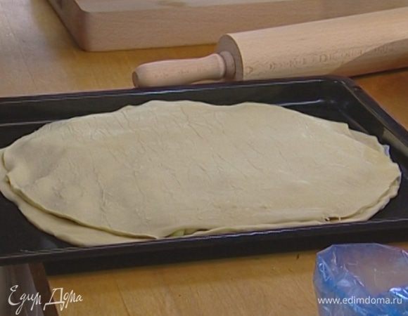 Уложить на противень сначала бумажный круг, смазанный сливочным маслом, затем один слой теста. Сверху ровно распределить начинку, отступив 1 см от края. Накрыть вторым слоем теста и аккуратно защипнуть края.
