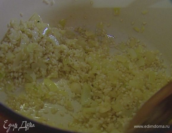 Добавить чеснок, цедру апельсина, всыпать рис, влить вино, посолить и перемешать. 