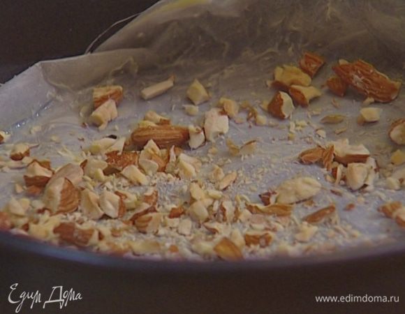 Круглую разъемную форму выстелить бумагой для выпечки, смазанной оставшимся сливочным маслом, высыпать на нее миндаль.
